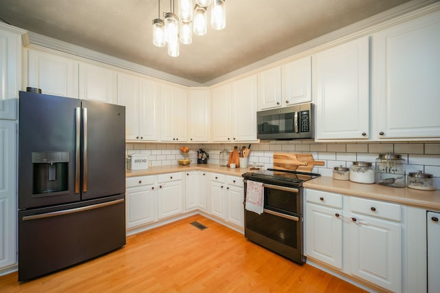 kitchen featuring white cabinets, decorative backsplash, appliances with stainless steel finishes, decorative light fixtures, and light hardwood / wood-style floors