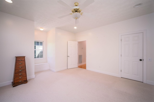 spare room with a textured ceiling, ceiling fan, and light carpet