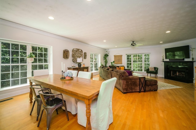 dining room with ceiling fan, light hardwood / wood-style floors, ornamental molding, and a textured ceiling