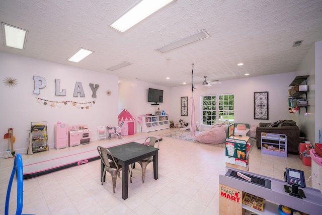 game room with ceiling fan and a textured ceiling