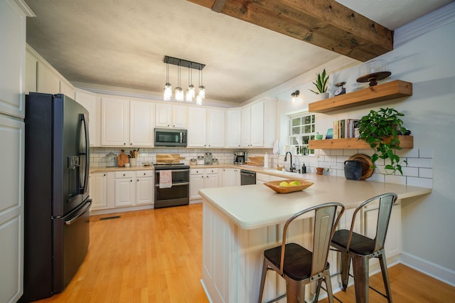 kitchen featuring white cabinetry, stainless steel appliances, kitchen peninsula, pendant lighting, and a kitchen bar