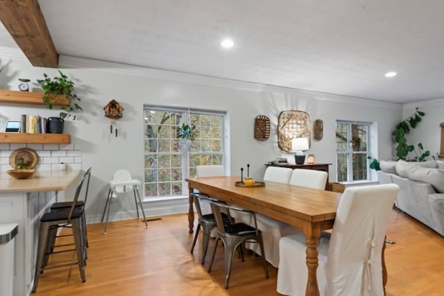 dining space with beamed ceiling, crown molding, and light hardwood / wood-style floors