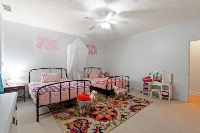 bedroom with ceiling fan, light colored carpet, and a textured ceiling