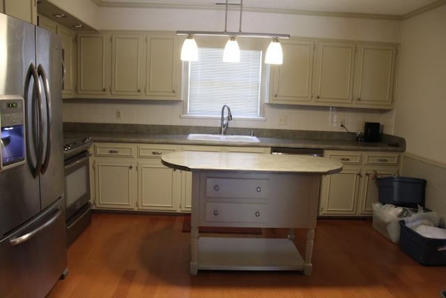 kitchen featuring sink, hanging light fixtures, crown molding, wood-type flooring, and appliances with stainless steel finishes