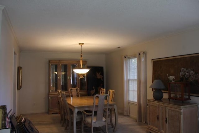 dining space with crown molding and light carpet