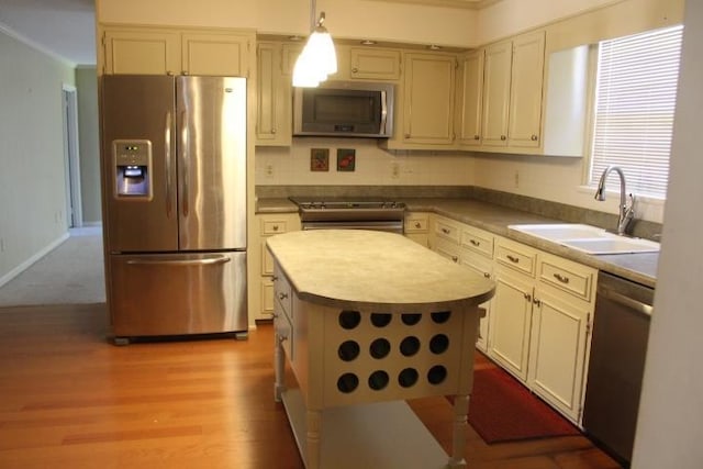 kitchen featuring sink, a center island, light hardwood / wood-style floors, decorative light fixtures, and appliances with stainless steel finishes