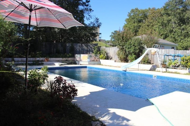 view of swimming pool with a diving board and a water slide