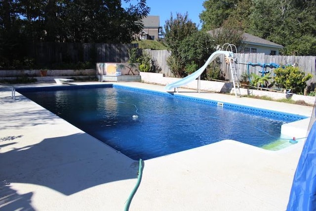 view of pool featuring a diving board, a water slide, and a patio