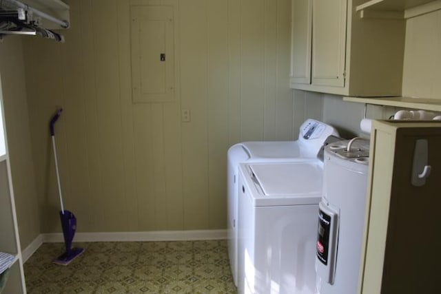 clothes washing area with wood walls, cabinets, independent washer and dryer, and electric panel