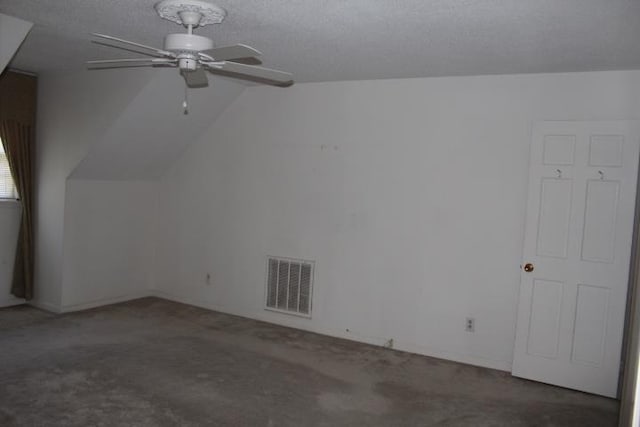 additional living space featuring ceiling fan, dark carpet, lofted ceiling, and a textured ceiling