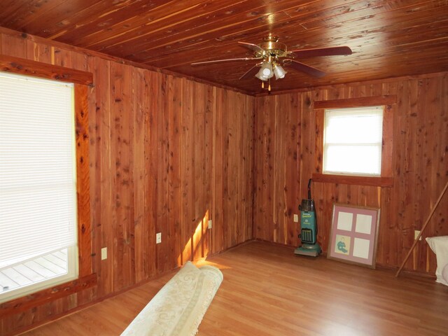 empty room with wood walls, ceiling fan, wooden ceiling, and light hardwood / wood-style floors