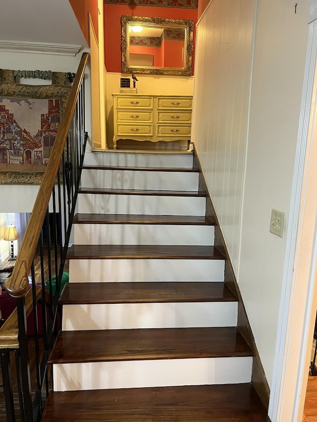  - staircase featuring wood finished floors and crown molding