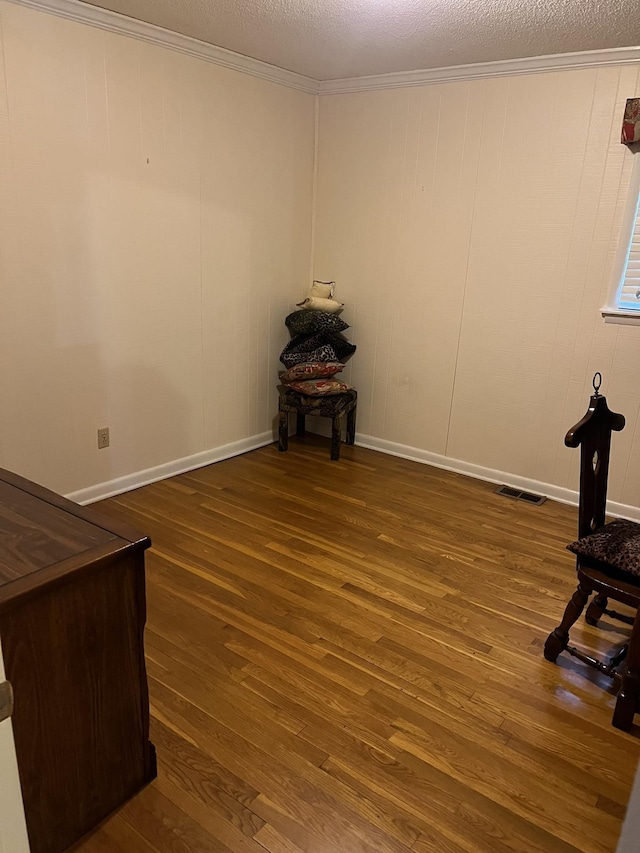  - spare room featuring wood finished floors, ornamental molding, and a textured ceiling