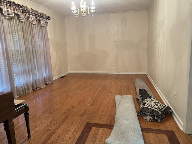  - spare room with a chandelier, crown molding, wood finished floors, and a textured ceiling