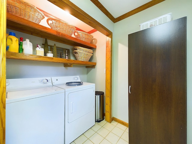 clothes washing area featuring light tile patterned floors, washing machine and dryer, and crown molding