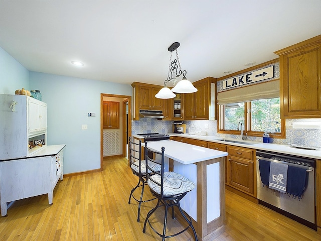 kitchen with sink, stainless steel appliances, decorative light fixtures, a breakfast bar area, and a kitchen island