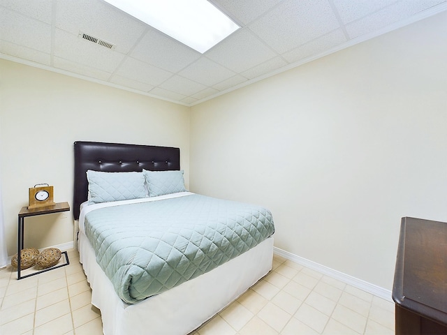 bedroom with a drop ceiling and light tile patterned floors