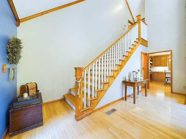 staircase featuring hardwood / wood-style flooring, ornamental molding, and a high ceiling