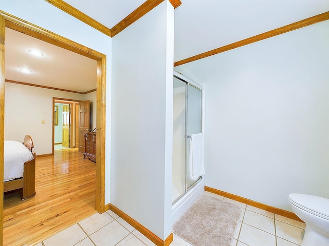 bathroom with tile patterned floors, toilet, ornamental molding, and a shower with door