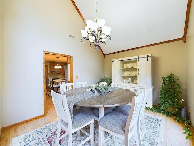 dining room with light wood-type flooring, high vaulted ceiling, an inviting chandelier, and crown molding