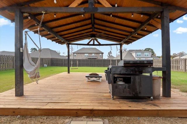 wooden deck featuring a gazebo, ceiling fan, a lawn, and a fire pit