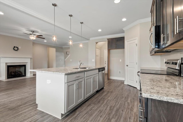 kitchen with sink, hanging light fixtures, an island with sink, appliances with stainless steel finishes, and light stone counters