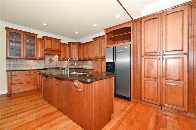 kitchen featuring sink, a breakfast bar area, stainless steel fridge with ice dispenser, a center island with sink, and light hardwood / wood-style floors