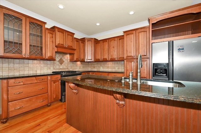 kitchen featuring tasteful backsplash, sink, dark stone counters, stainless steel refrigerator with ice dispenser, and gas range oven