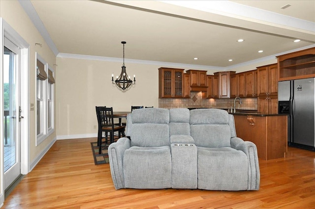 living room with ornamental molding, sink, a chandelier, and light hardwood / wood-style flooring
