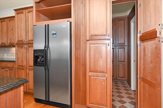 kitchen featuring dark stone counters, stainless steel fridge, and decorative backsplash
