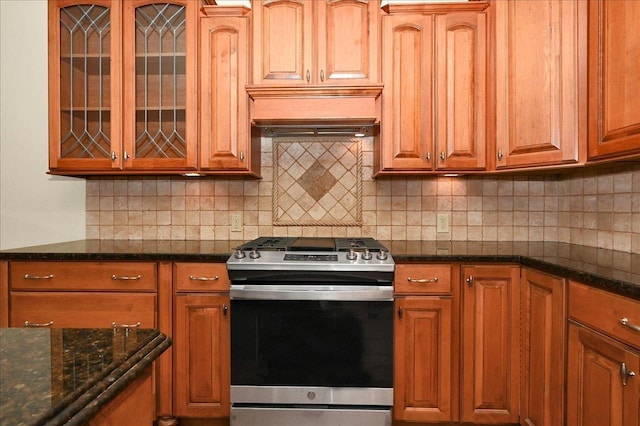 kitchen with stainless steel range with gas cooktop, decorative backsplash, and dark stone countertops