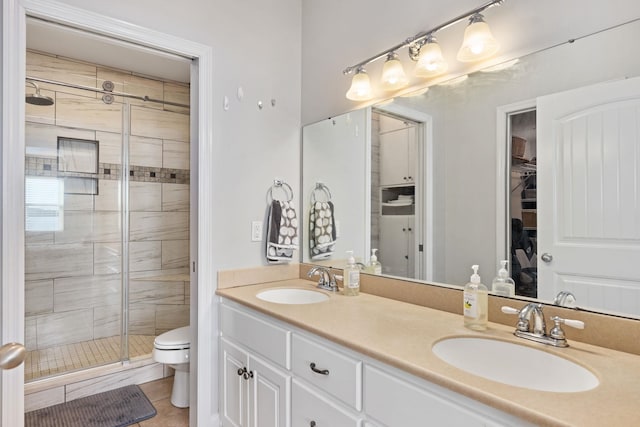 bathroom featuring tile patterned flooring, vanity, an enclosed shower, and toilet