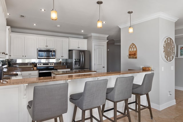 kitchen with white cabinets, ornamental molding, appliances with stainless steel finishes, light tile patterned flooring, and kitchen peninsula