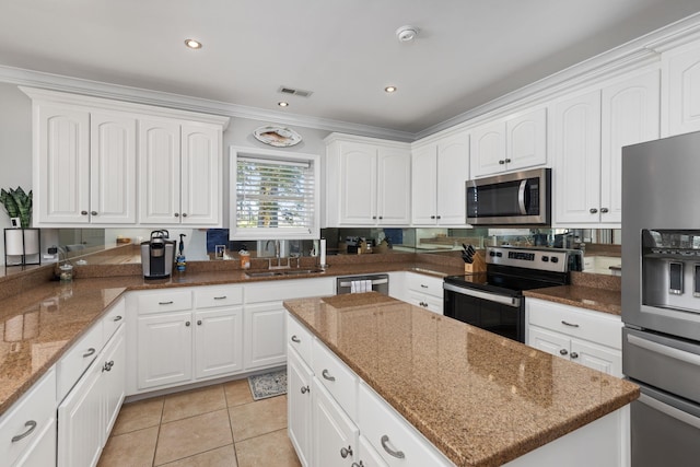 kitchen with white cabinets, sink, dark stone countertops, light tile patterned floors, and appliances with stainless steel finishes