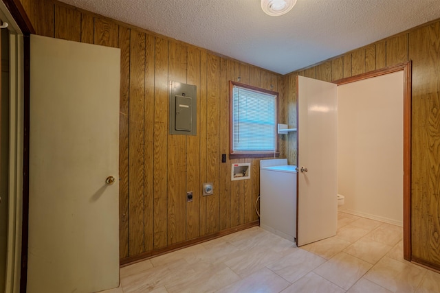  - laundry room featuring electric panel, a textured ceiling, wooden walls, baseboards, and washer / clothes dryer