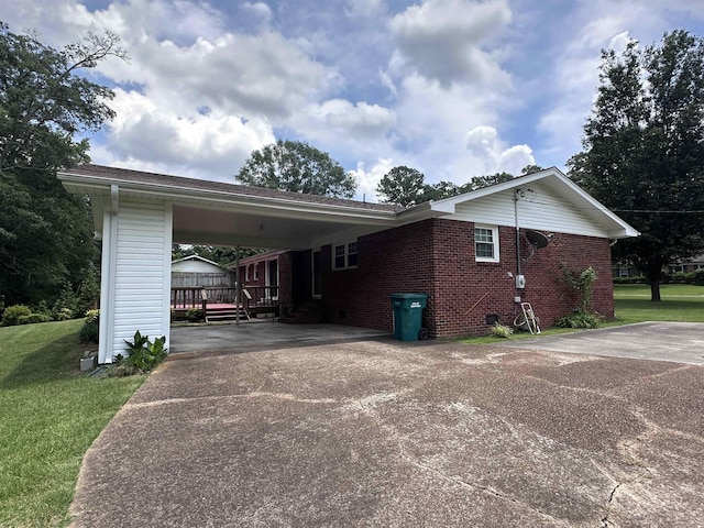 - view of side of home featuring concrete driveway, a yard, brick siding, and a carport