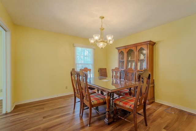  - dining space featuring a chandelier, light wood-style floors, and baseboards