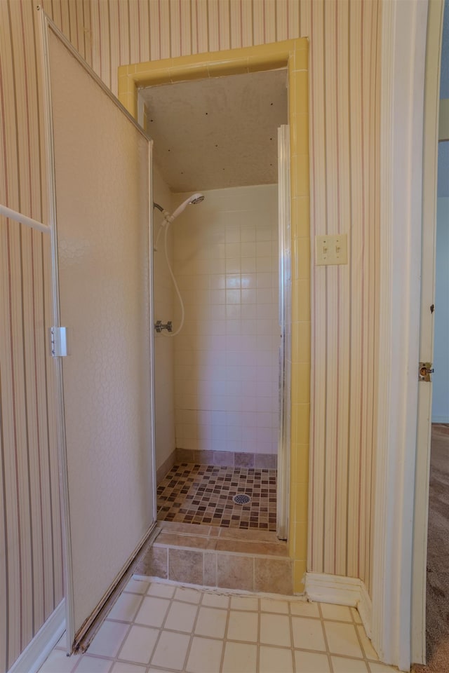  - bathroom with a shower stall, wallpapered walls, and baseboards