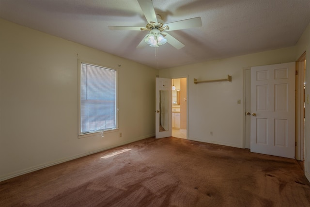  - unfurnished bedroom with carpet floors, baseboards, ensuite bath, and ceiling fan