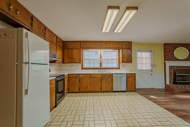  - kitchen with freestanding refrigerator, black range with electric stovetop, dishwasher, a sink, and brown cabinetry