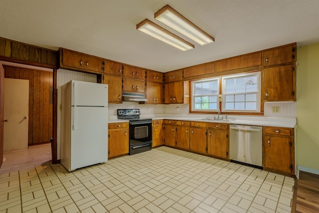  - kitchen featuring black range with electric cooktop, freestanding refrigerator, stainless steel dishwasher, a sink, and under cabinet range hood