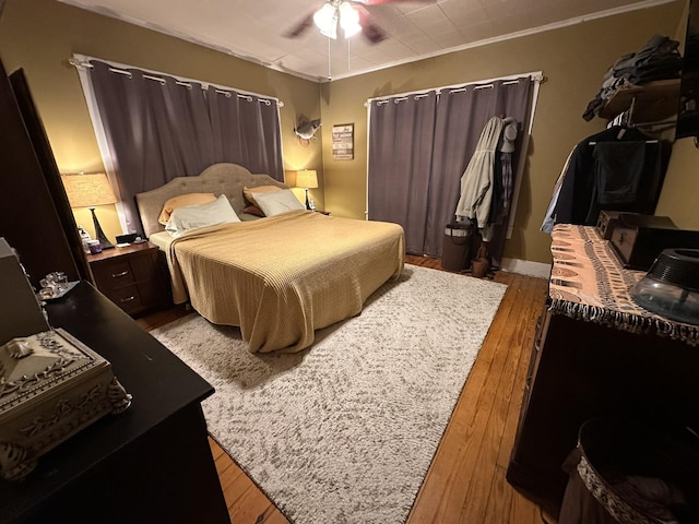 bedroom with wood finished floors, a ceiling fan, and crown molding