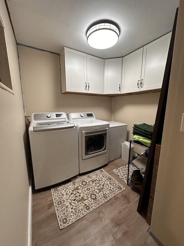 laundry room featuring washer and clothes dryer, wood finished floors, and cabinet space