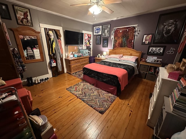 bedroom with ceiling fan, ornamental molding, a closet, and wood finished floors