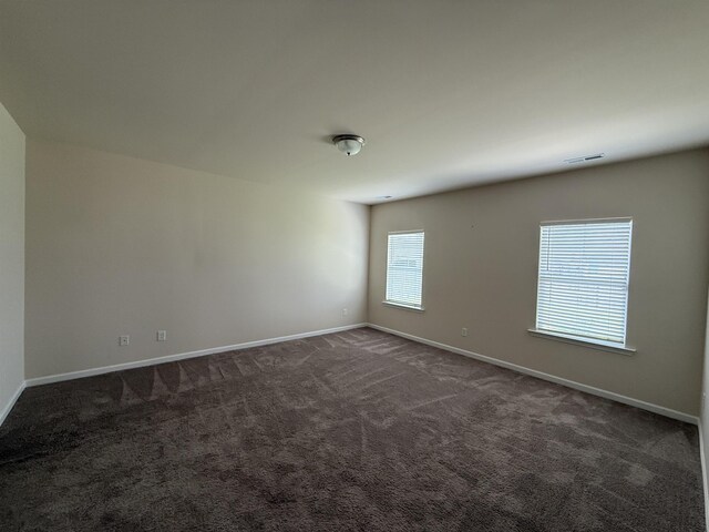  - empty room featuring baseboards and dark carpet