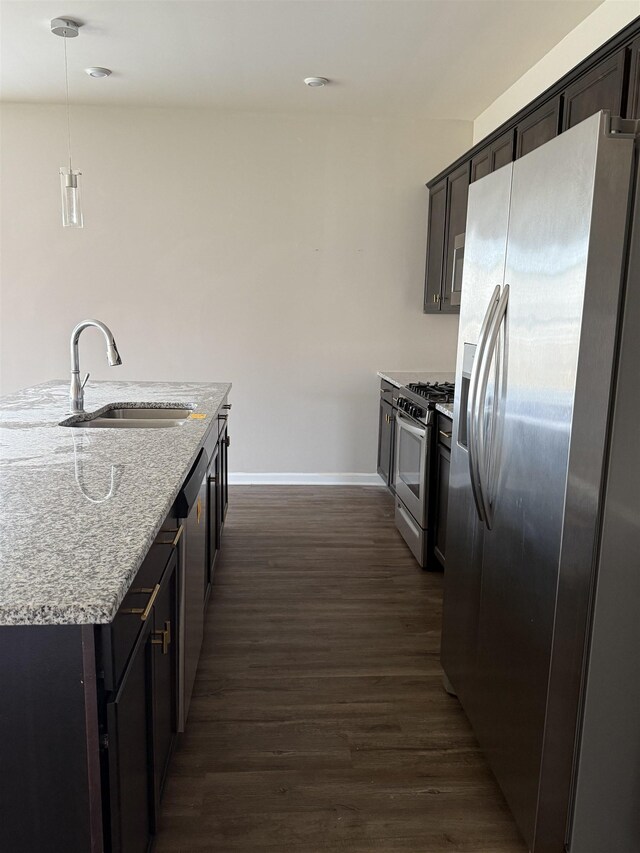  - kitchen with stainless steel appliances, a sink, baseboards, dark wood finished floors, and light stone countertops