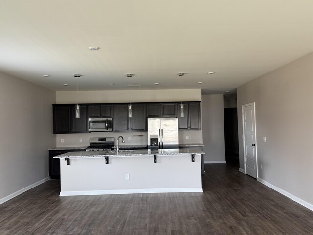  - kitchen with appliances with stainless steel finishes, a sink, a large island with sink, baseboards, and dark wood finished floors