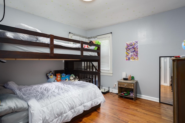  - bedroom with wood finished floors and a baseboard heating unit