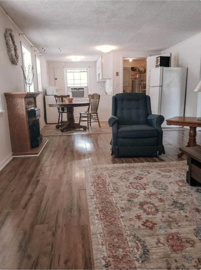 living room with water heater, a textured ceiling, cooling unit, and wood finished floors