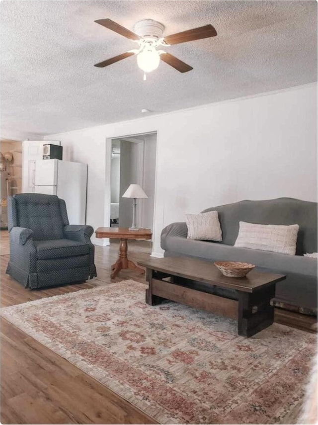 living area with a textured ceiling, ceiling fan, and wood finished floors